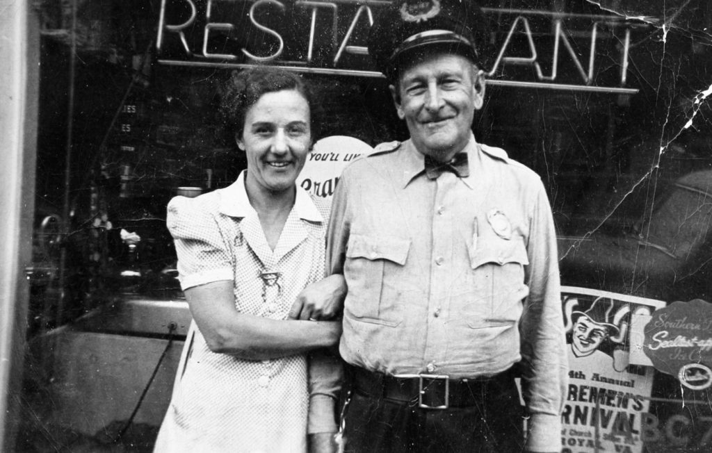 Edgar "Doc" Smith (right) of the Front Royal Police department with Dora Strickler in front of Stricker's Restaurant, Front Royal, circa 1938.